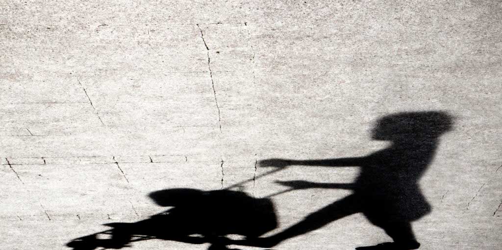 Distorted shadow of a parent pushing a baby stroller.