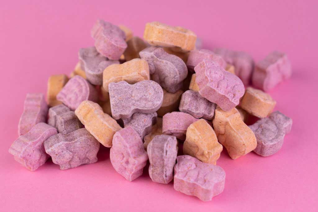 Kids multivitamins are piled on a pink background.