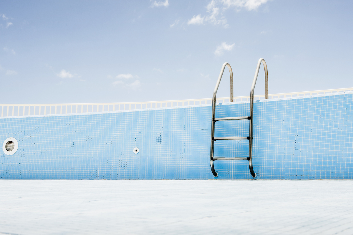 A pool ladder in an empty blue pool.
