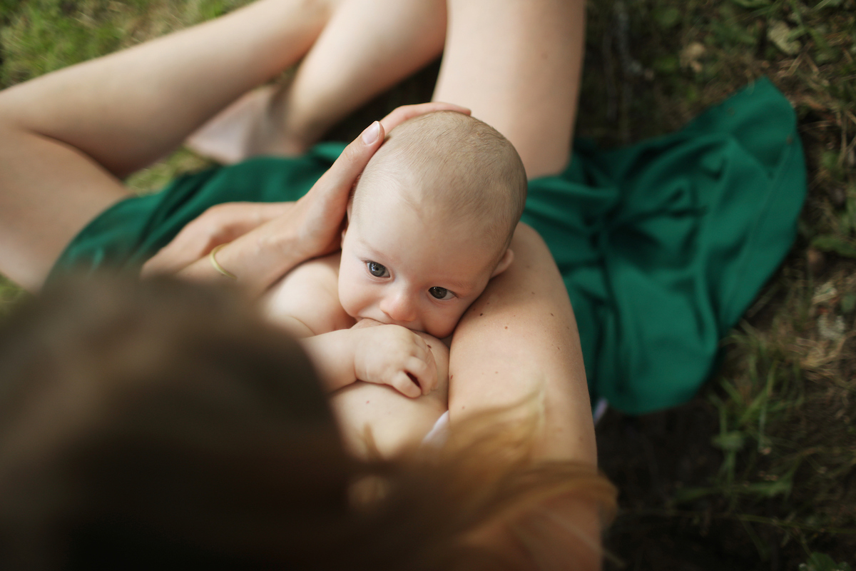 Overhead shot of a parent sitting cross-legged outside while breastfeeding a baby.