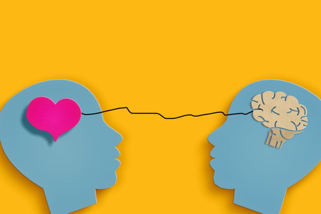 Blue paper cutouts on a yellow background. The cutout on the left has a heart in the brain, the one on the right has a brain.
