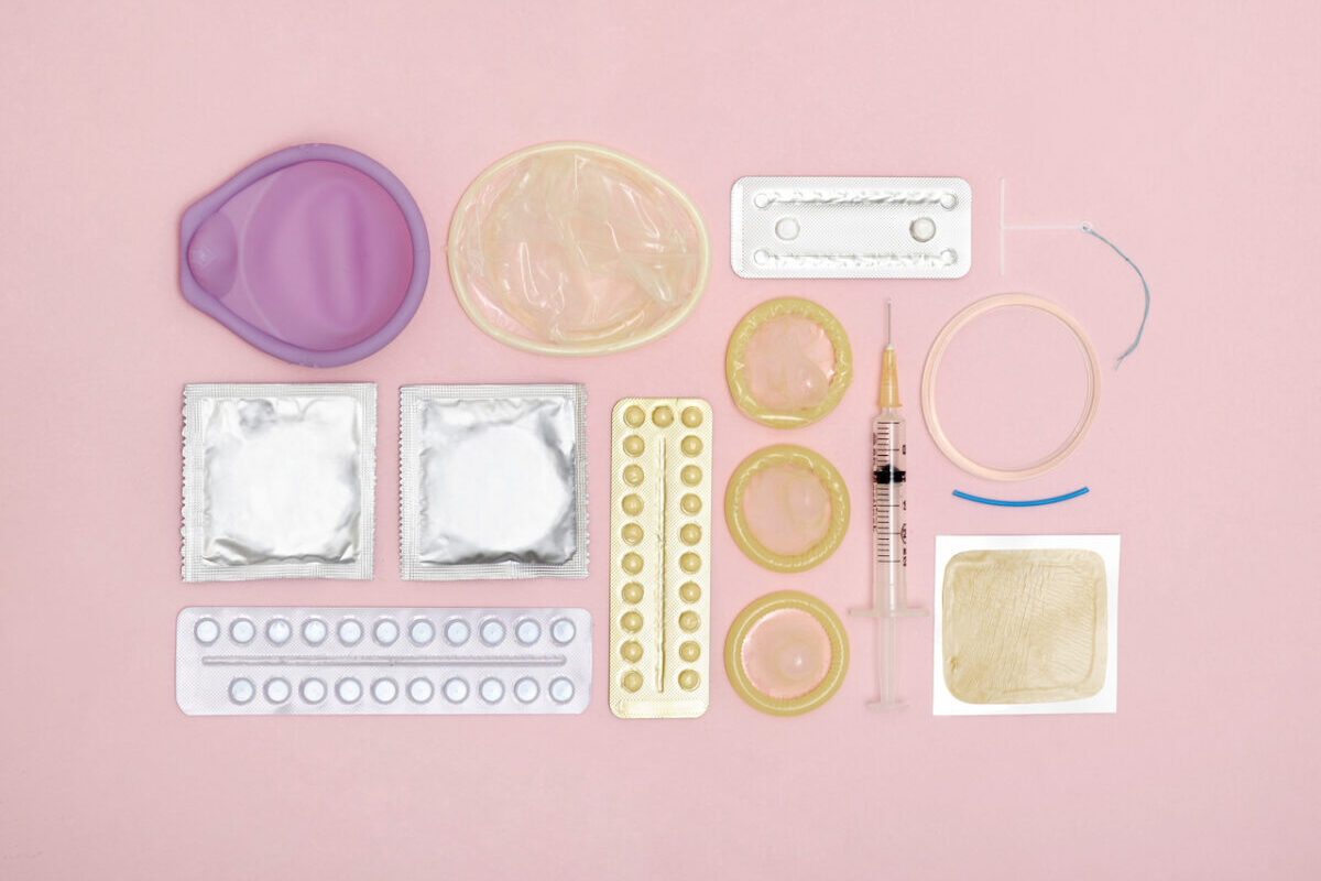 Different types of contraception are laid out on a pink background.