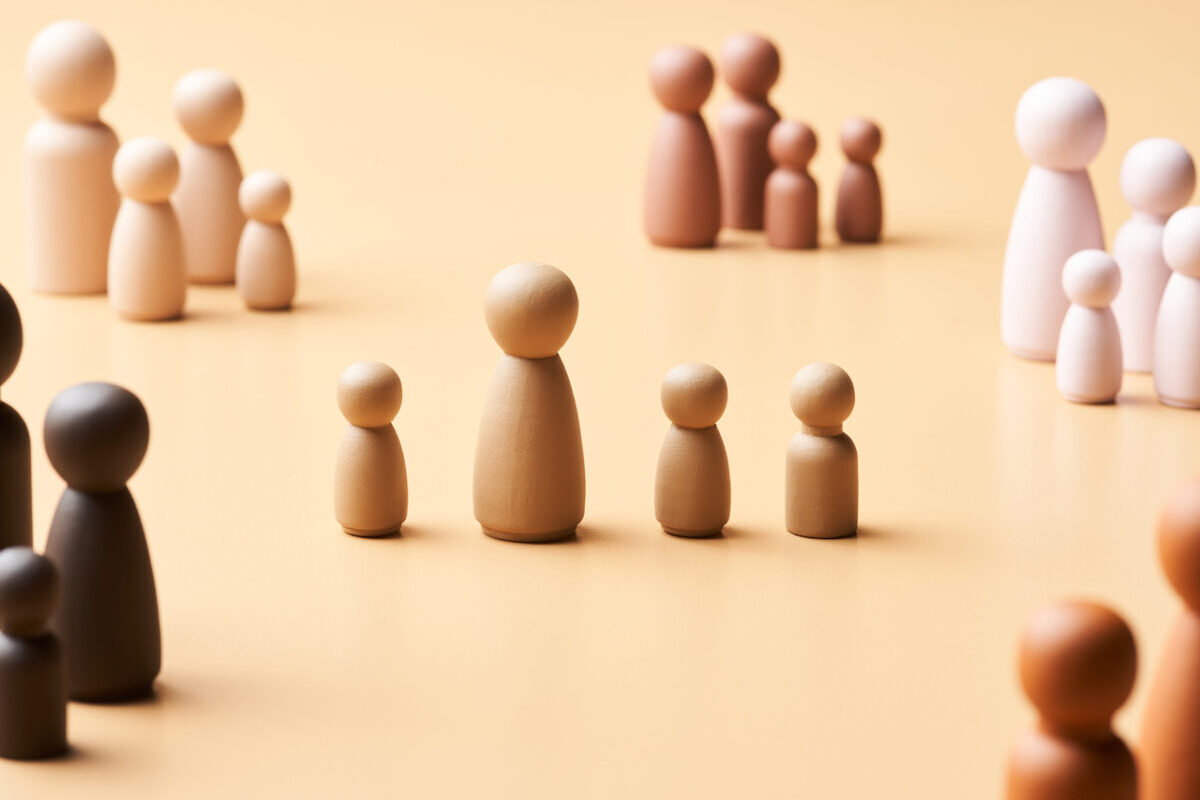 Figurines of wooden families with different numbers of family members are arranged on a beige background