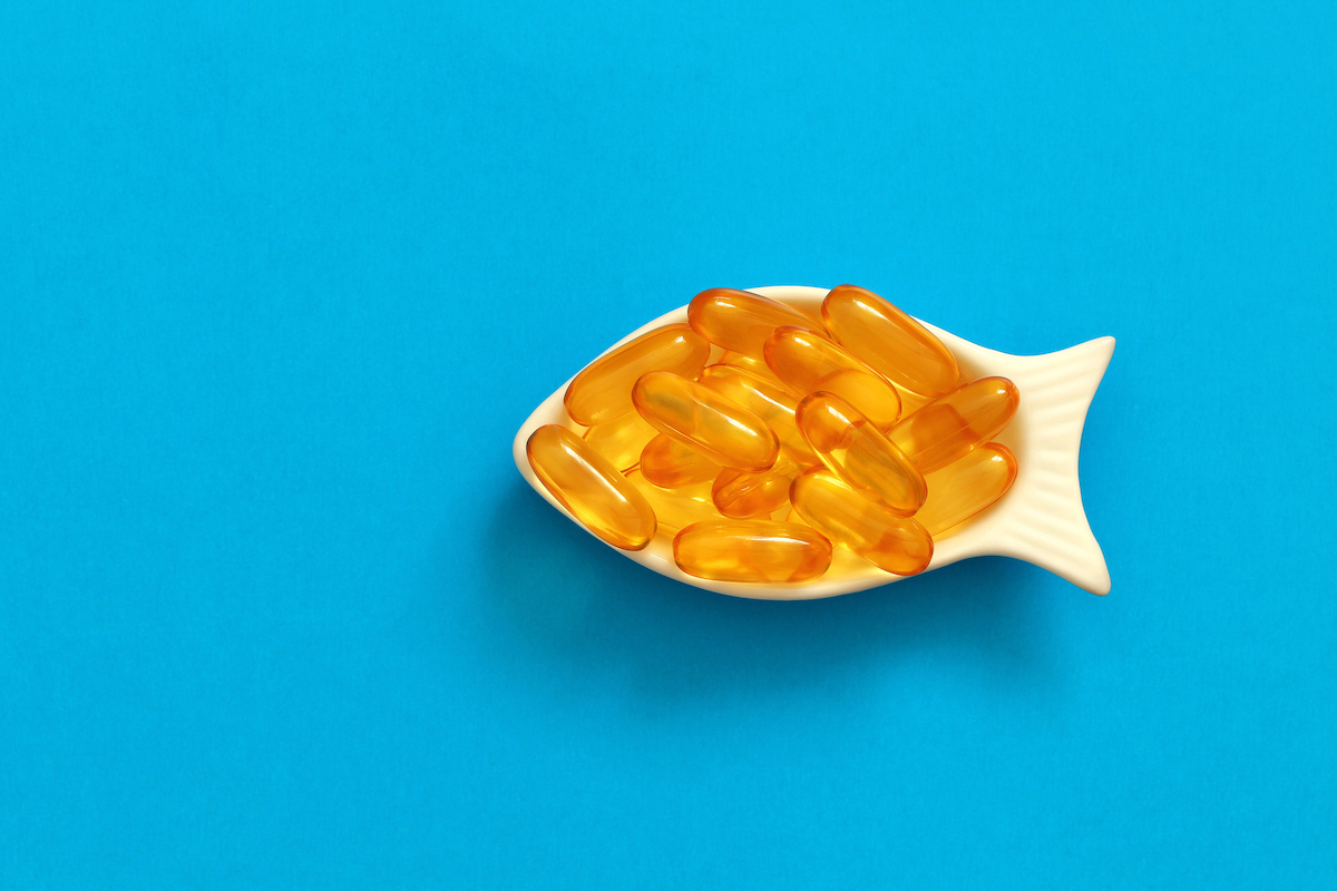 Yellow capsules in a dish shaped like a fish on a blue background.