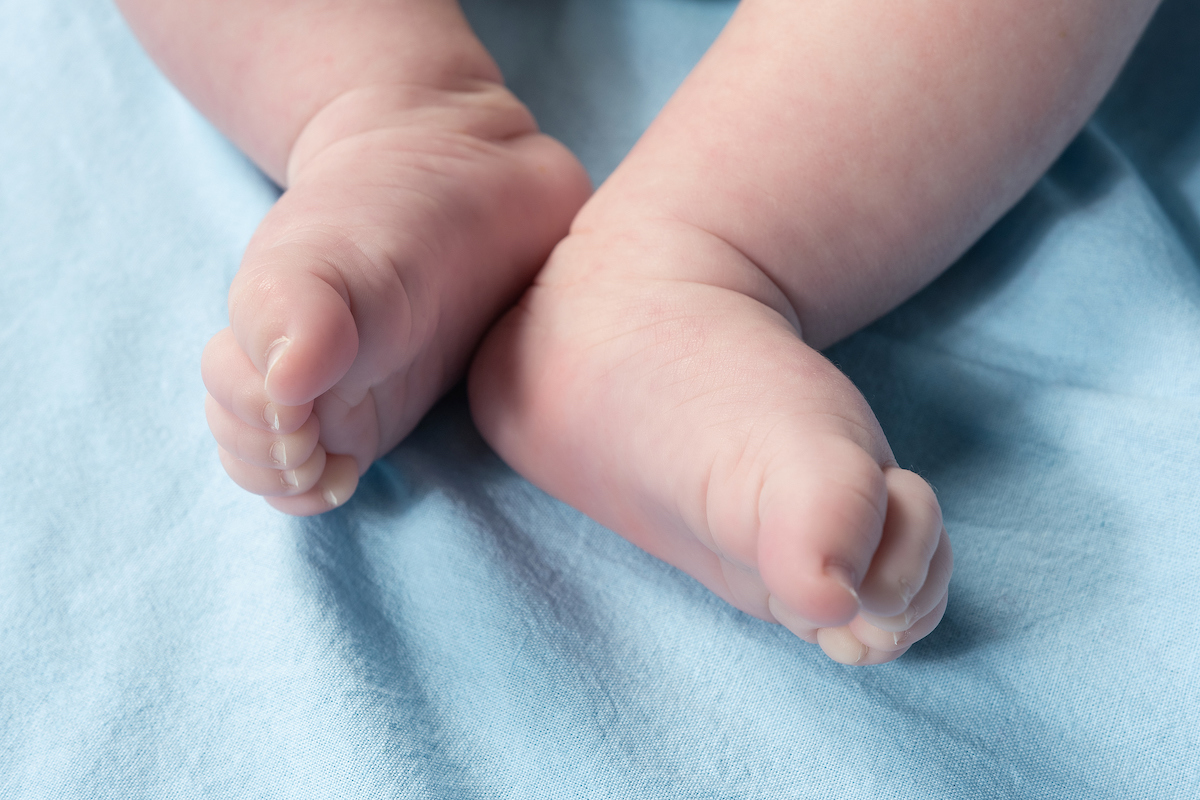 Close up view of newborn feet on a blue sheet.