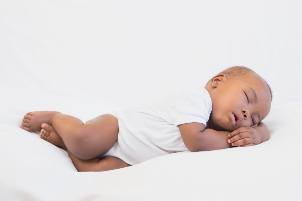 A baby sleep stretched across a white pillow.
