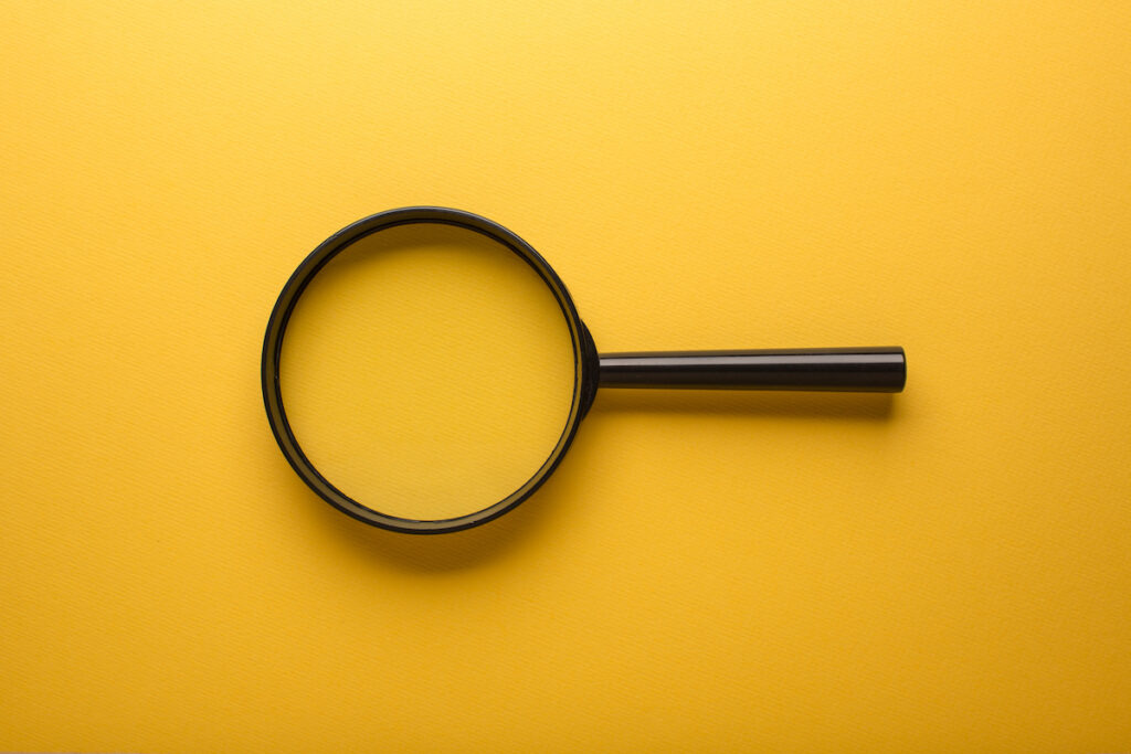 Black magnifying glass on a yellow background.