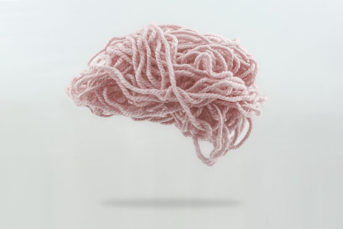 An illustration of a brain made out of a tangle of pink wool thread.