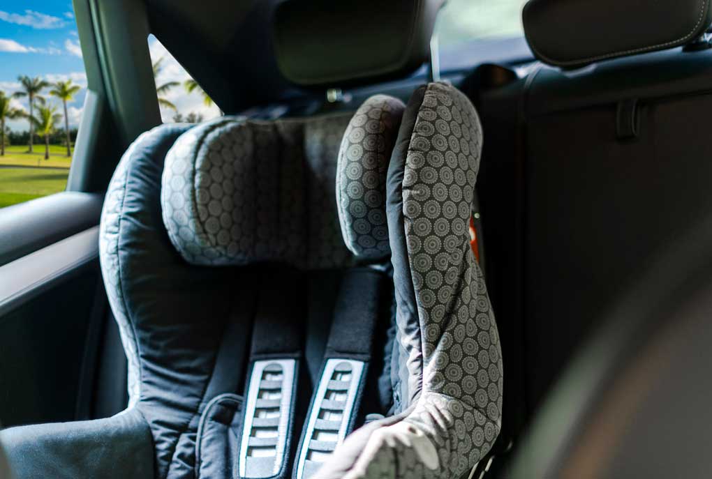 An empty car seat is seen in a car on a sunny, warm day.