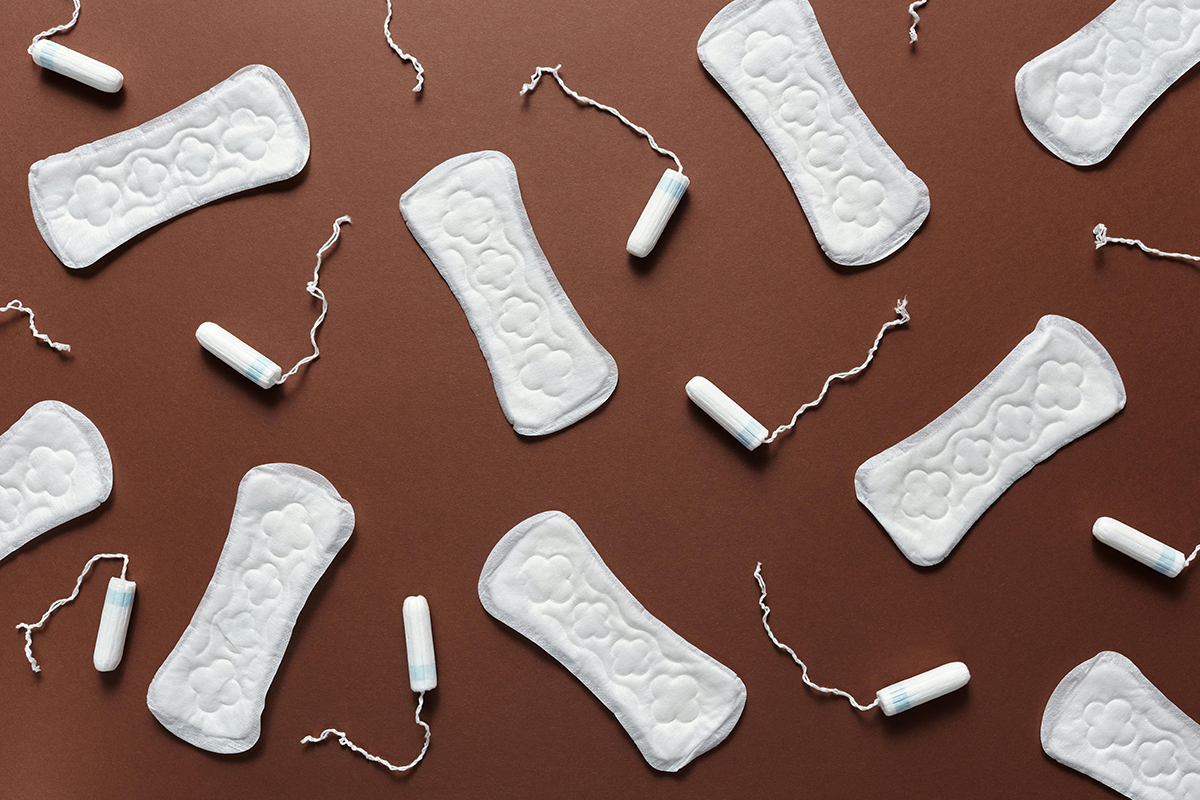 Artfully placed unwrapped tampons and pads on a brown background.