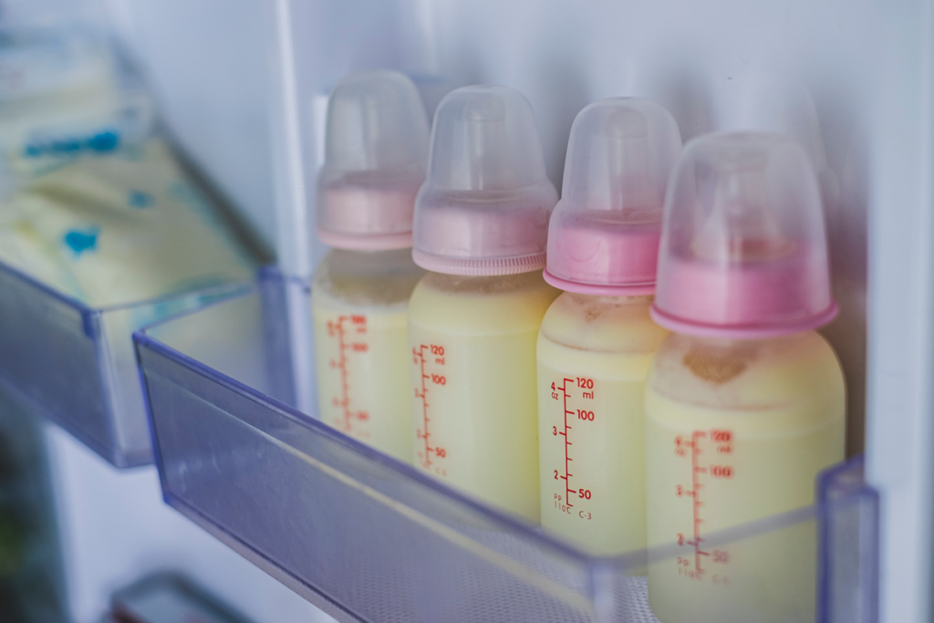 A freezer door shows bags and bottles of frozen breastmilk.