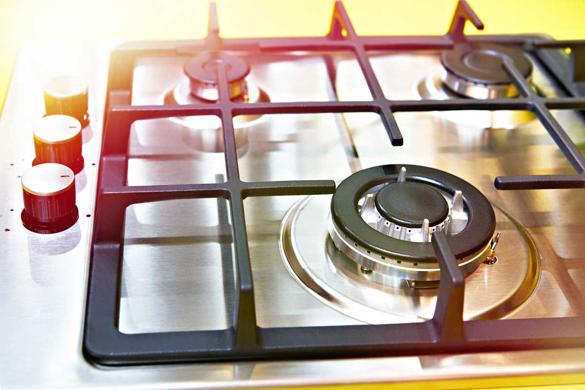 A close-up image of a gas stove against a yellow background.