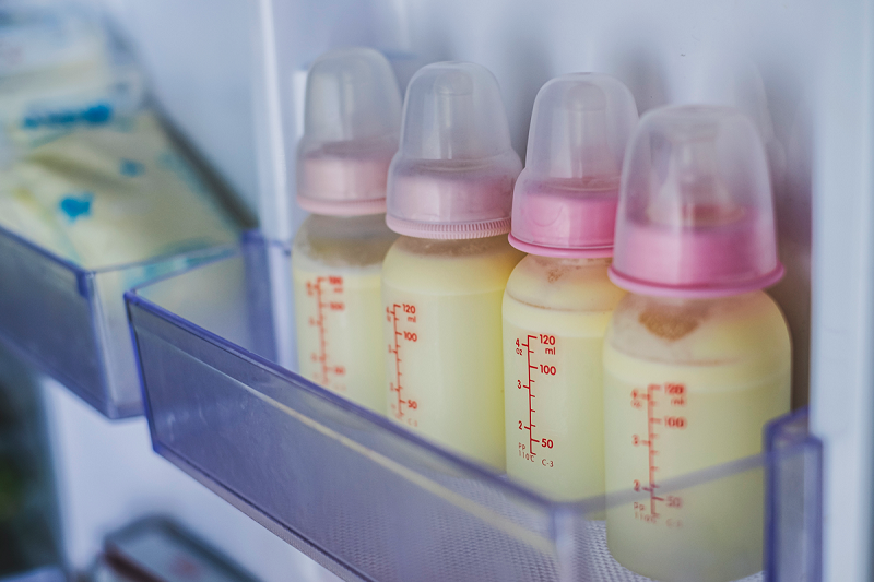 A freezer door shows bags and bottles of frozen breastmilk.