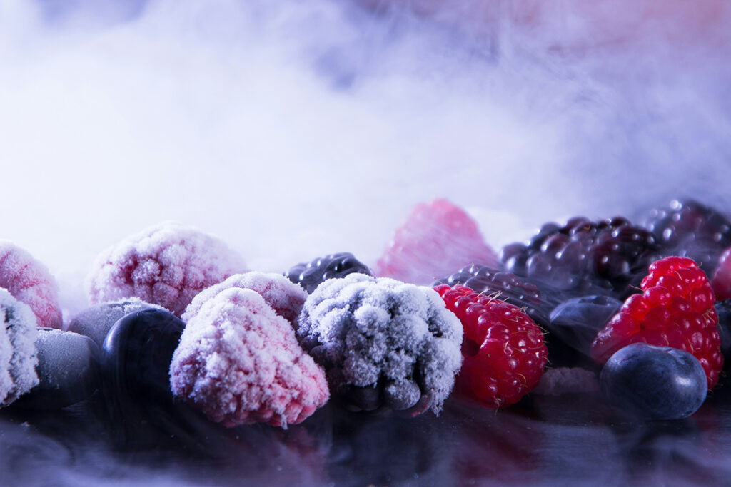 Frozen strawberries, blueberries, and blackberries next to unfrozen fruit.