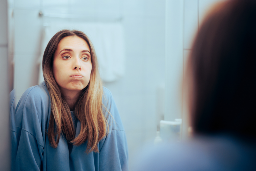 An anemic person looks worn down while looking into the mirror.