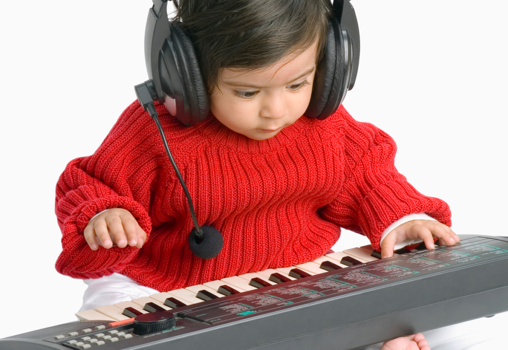 A baby DJ in a red sweater plays a kid song on a piano.