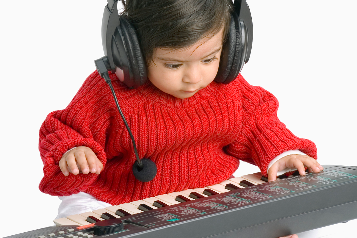 A baby DJ in a red sweater plays a kid song on a piano.