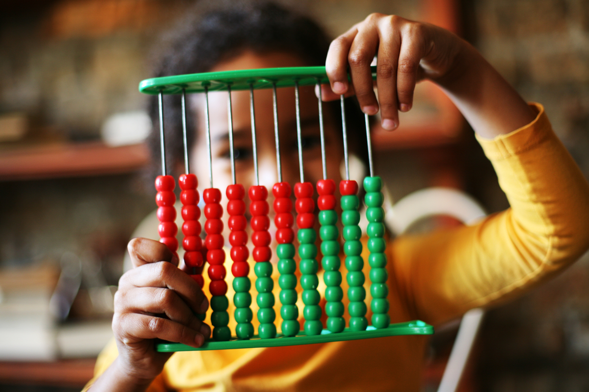 A child holds up an abacus with green and red beads arranged to look like a data chart.