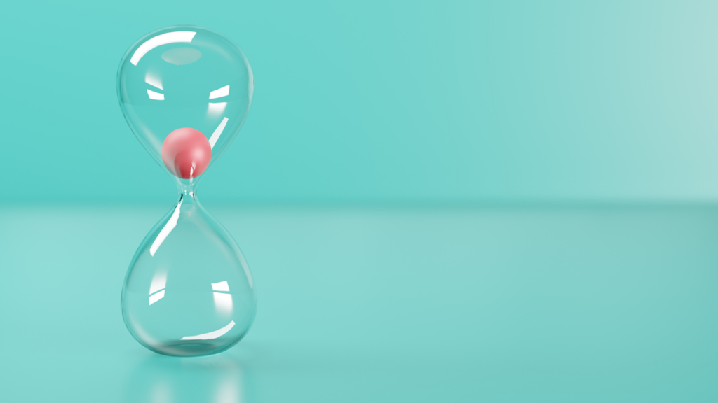 A glass hourglass is seen on a green background. It is clogged with a large ball to represent slow labor.