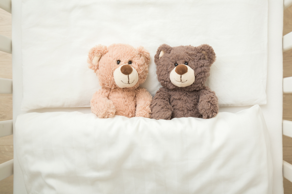 A top-down view of two teddy bears, side by side, in a crib.