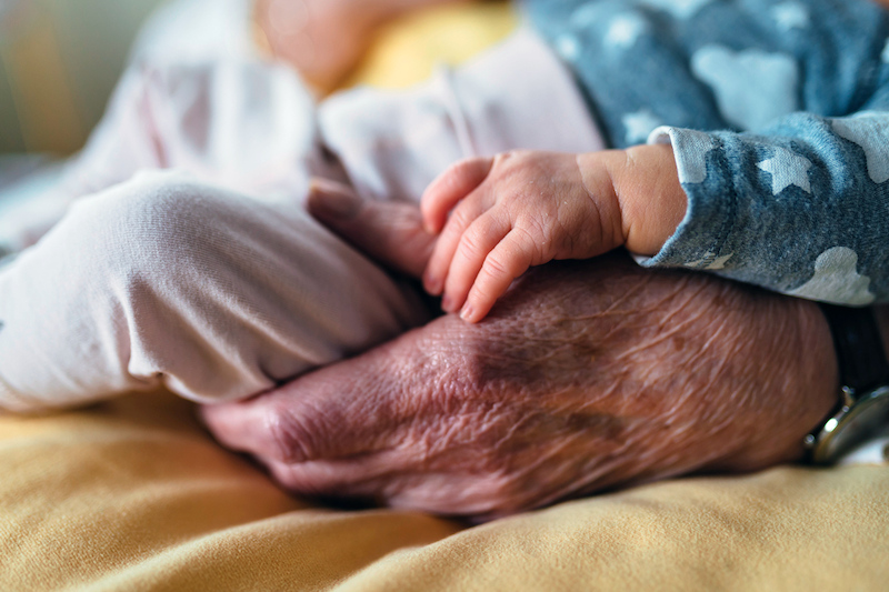 Close up of older person's hand holding child's hand