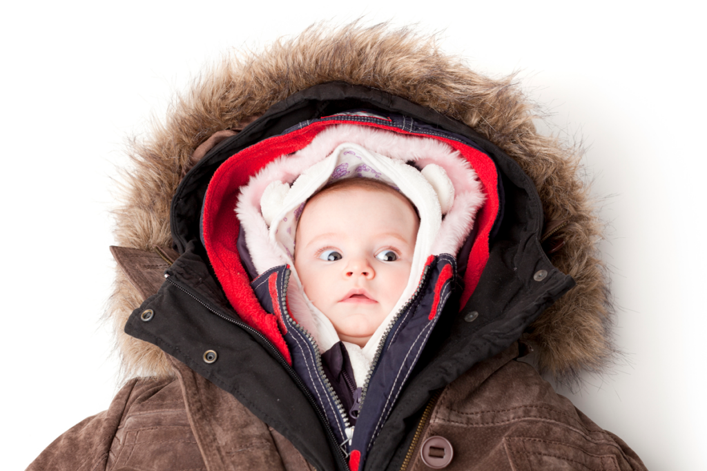 A baby wearing multiple layers of jackets looks confused.