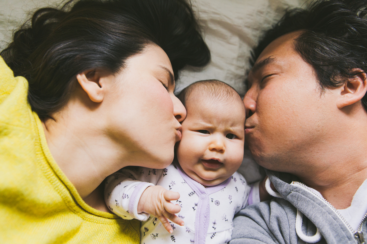 Two parents kiss a baby on either cheek.