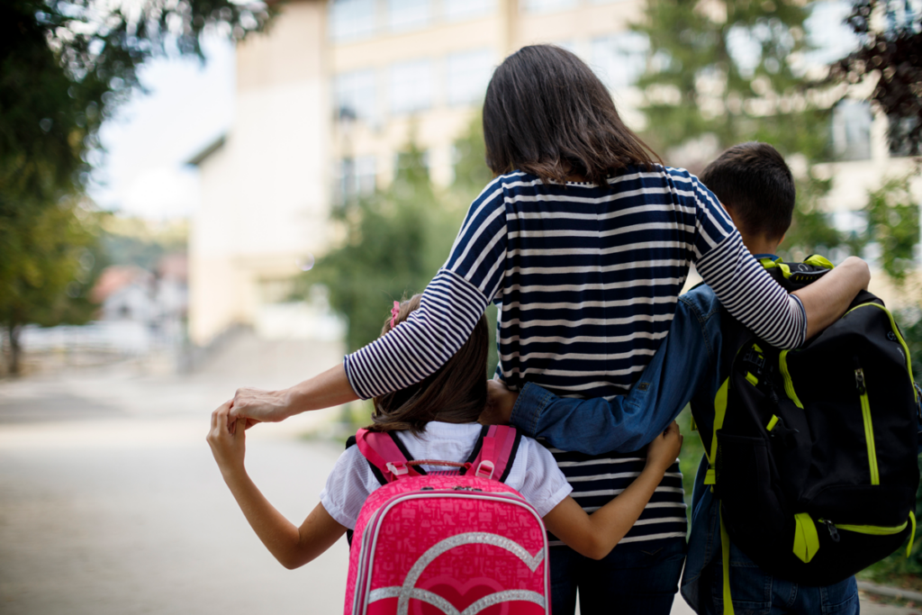 A parent hugs their children during school drop off.