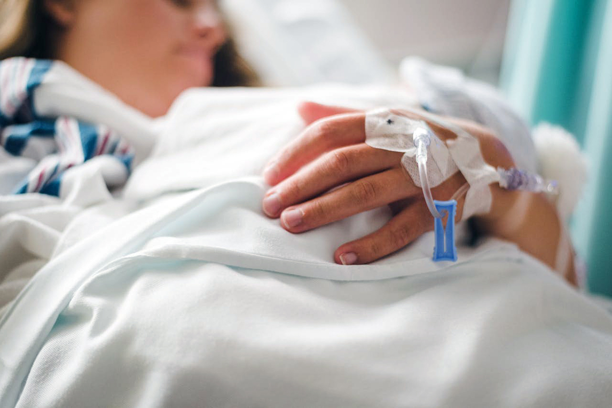 a patient in hospital with IV needles on the hand