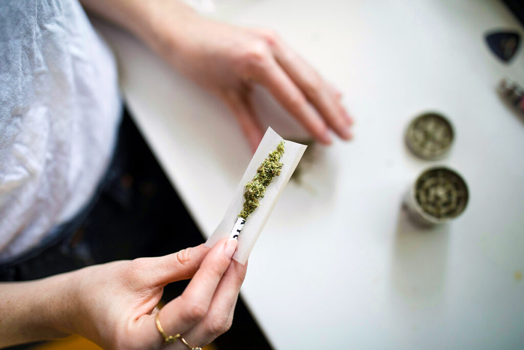 Person making a marijuana joint on a counter.