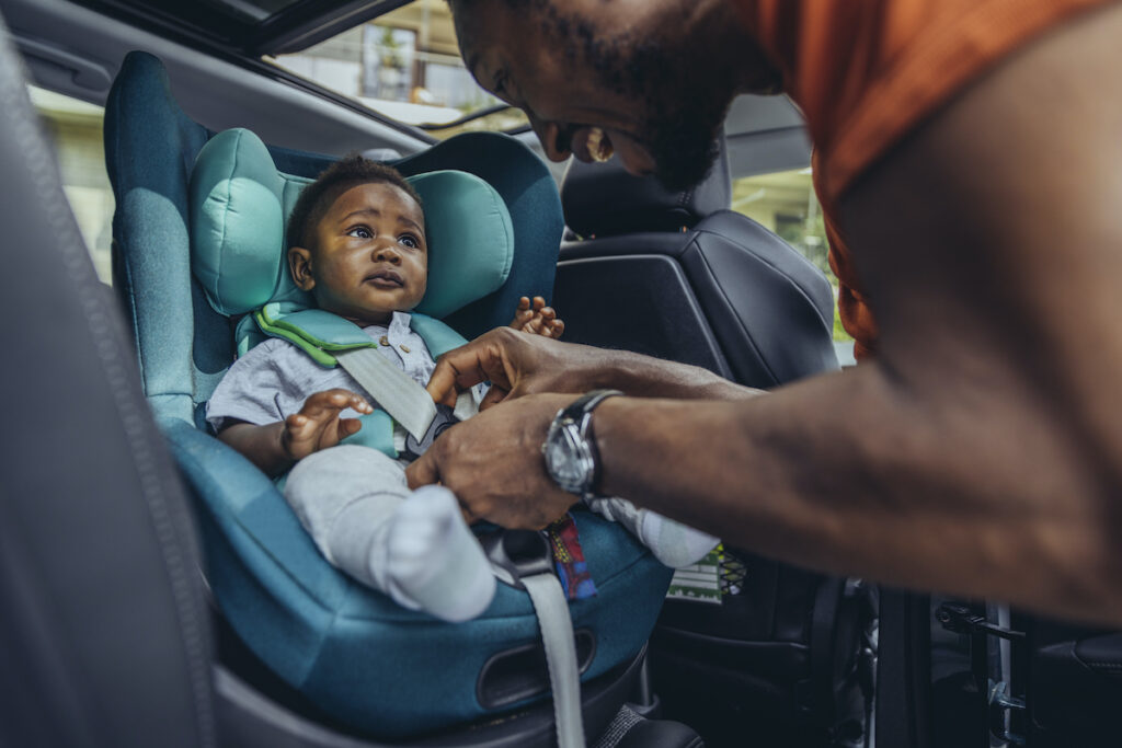 A man buckles a baby into a carseat
