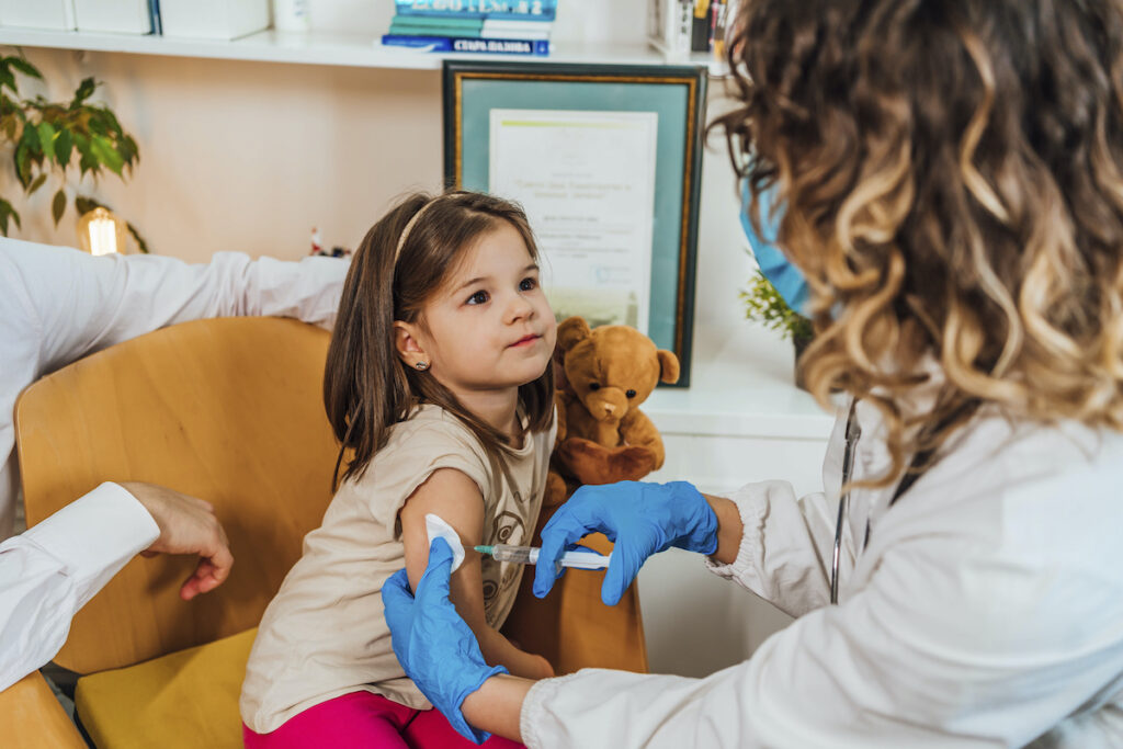 A toddler gets a shot from a doctor
