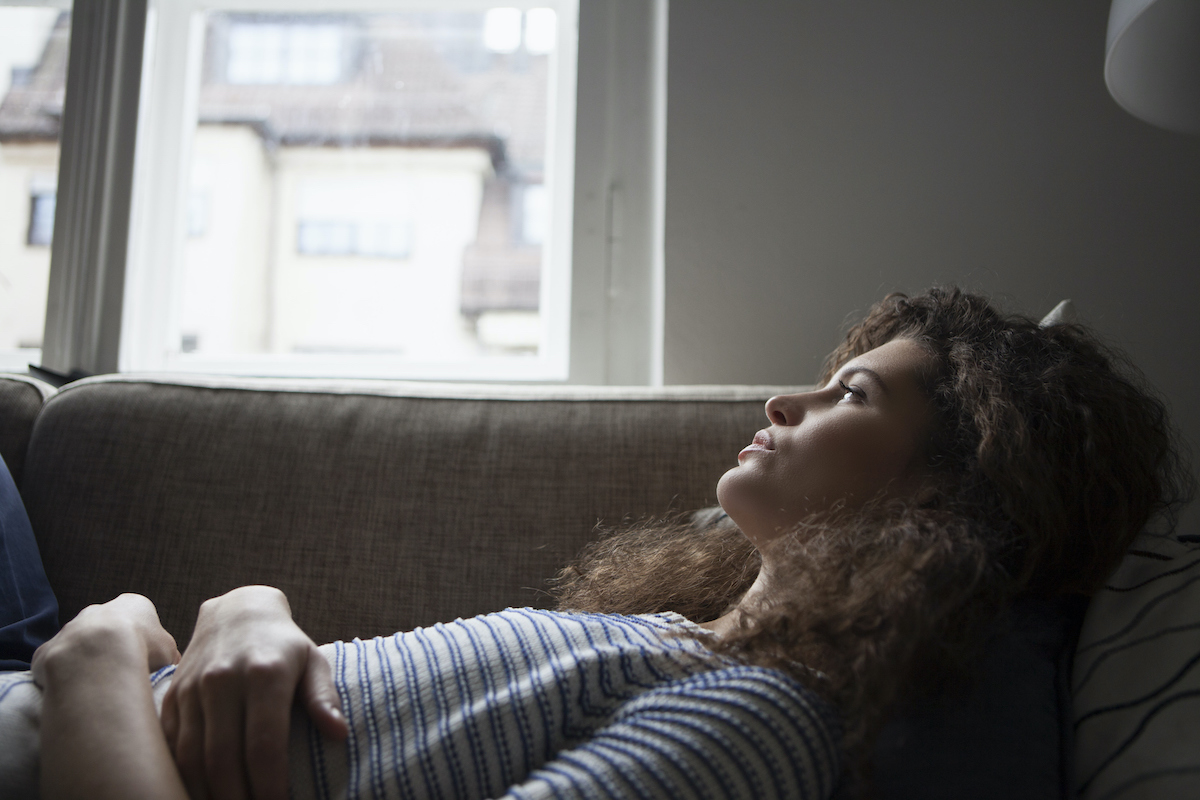 Woman laying on a couch looking out the window