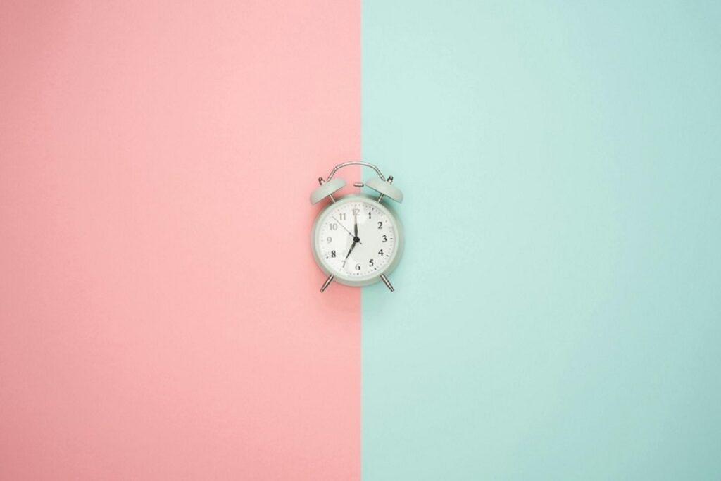 a small clock with a pink and green background