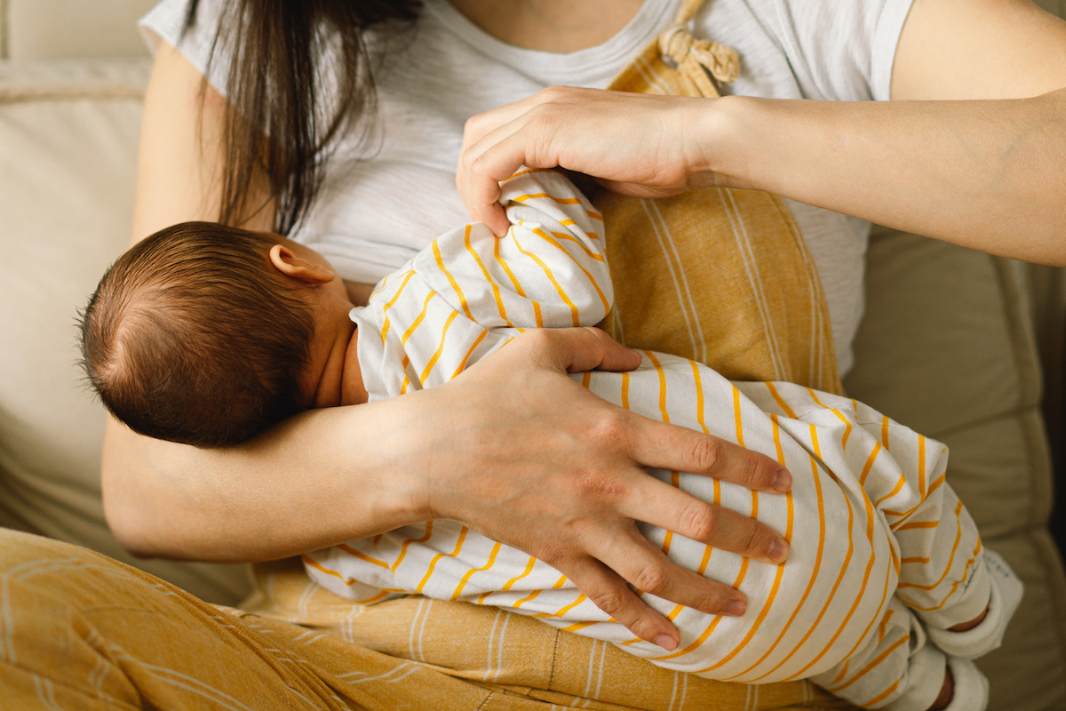 Parent holds a baby while breastfeeding.
