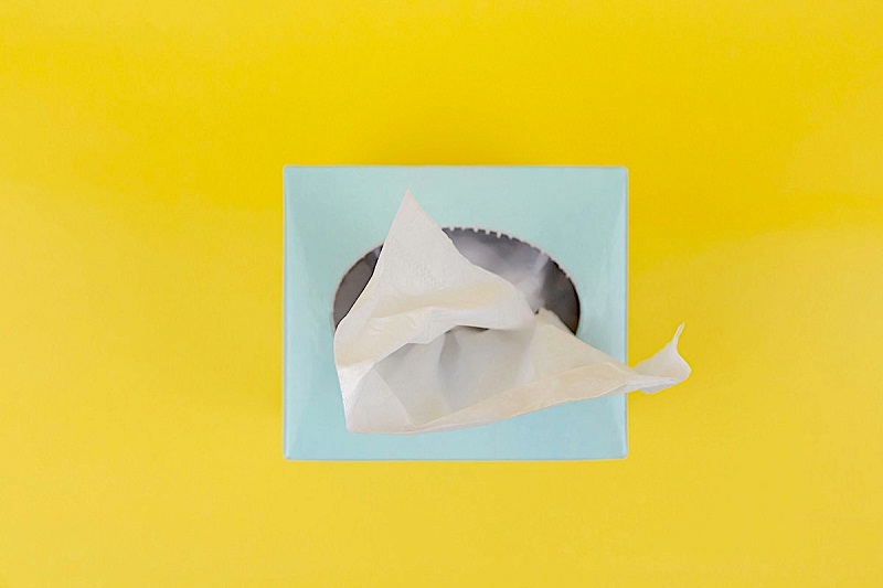 A light blue box of tissues is seen on a bright yellow background.