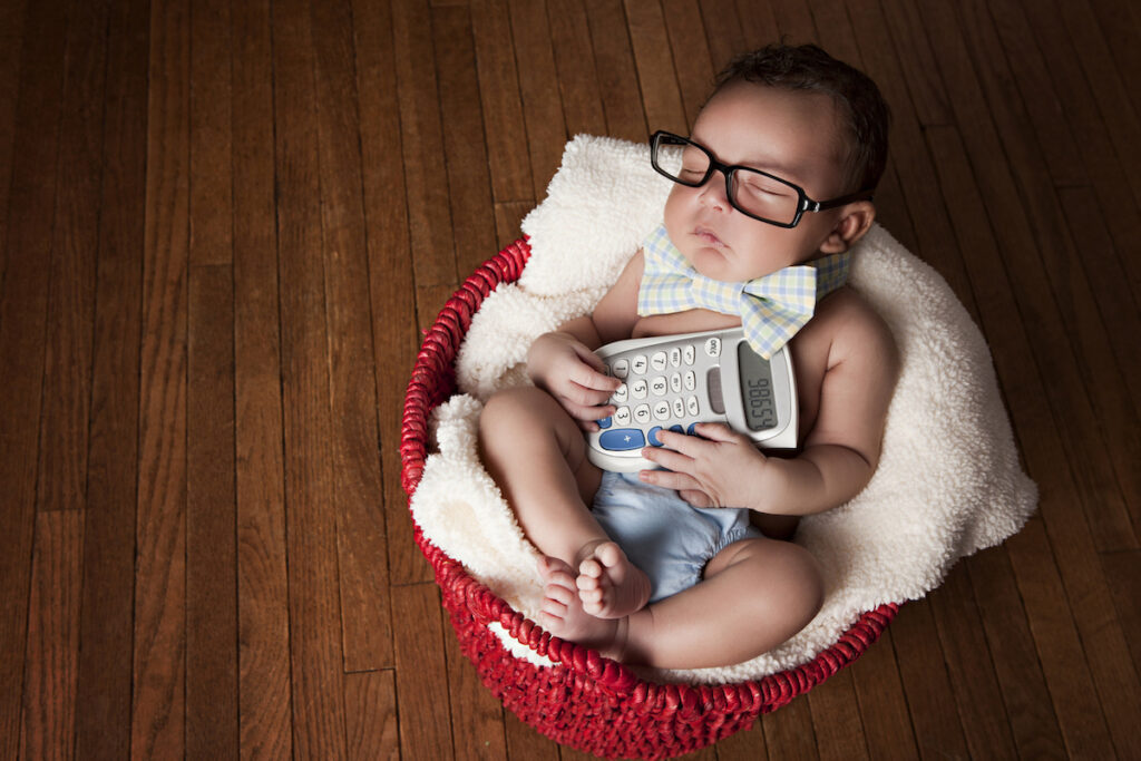 A newborn holds a calculator while sleeping.