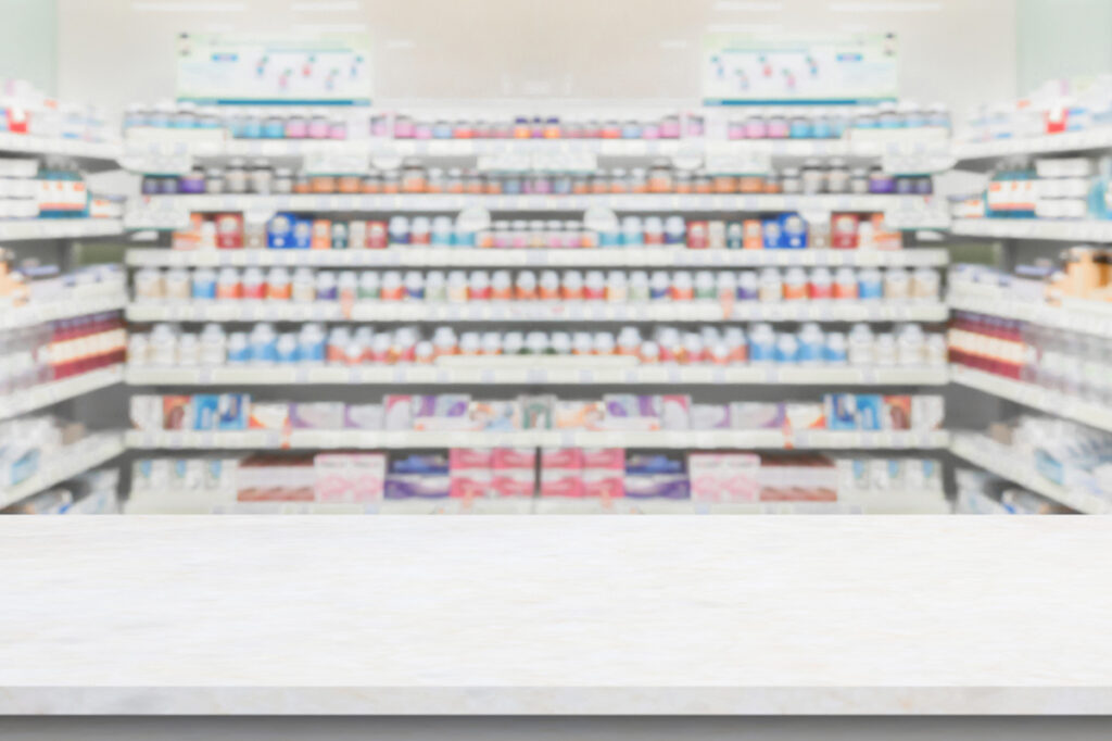 A view of a drugstore counter and pharmacy shelf with boxes.