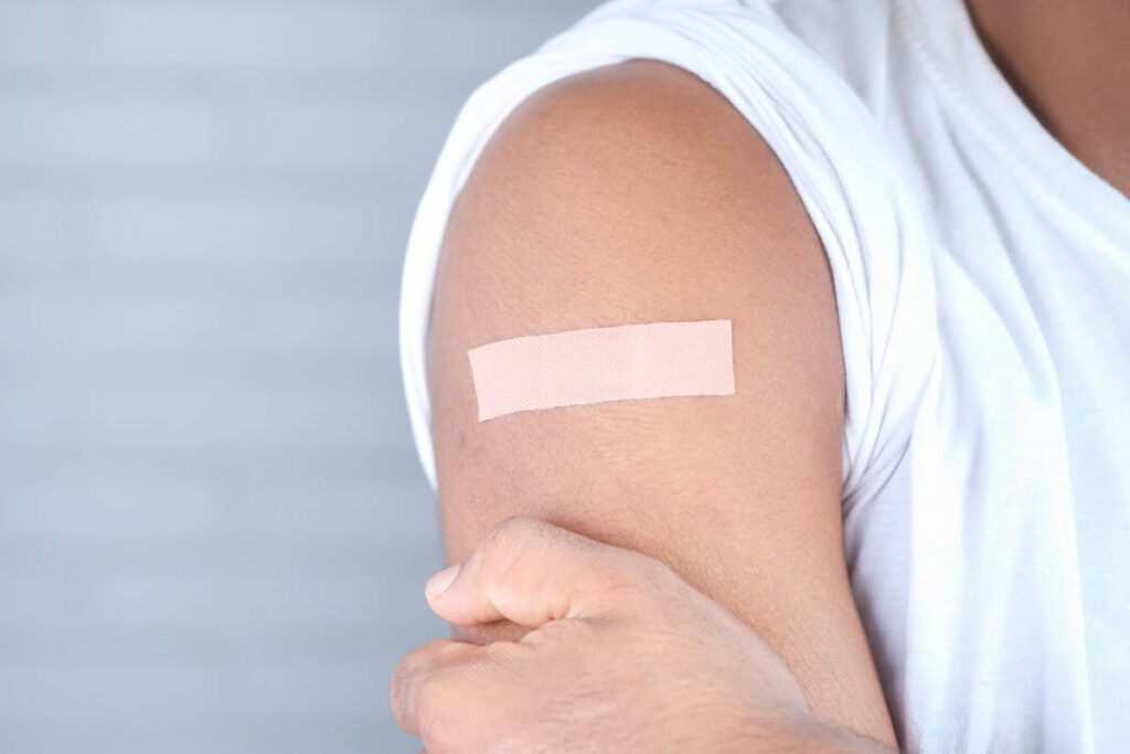 A person shows of a bandaid on their arm after a flu shot.