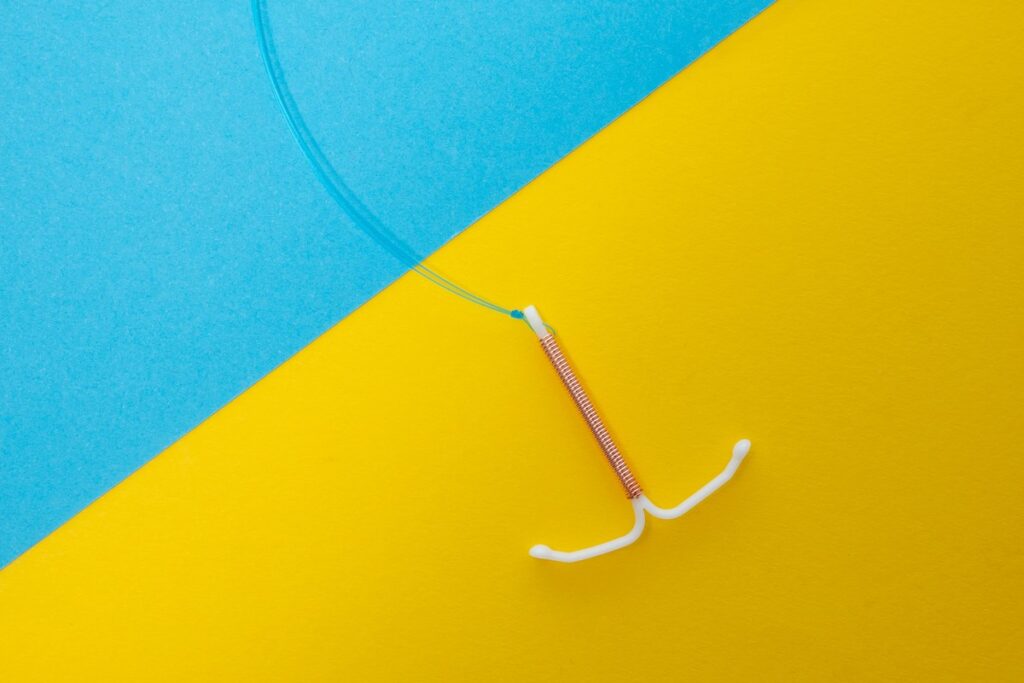 An IUD is seen on a blue and yellow background.