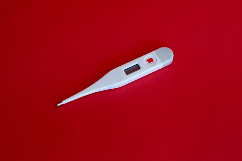 A thermometer is seen on a bright red background.