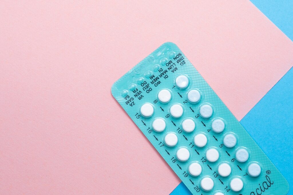 Birth control pills on pink and blue background