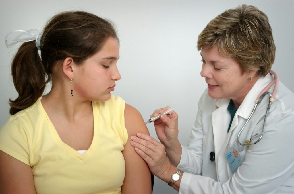 Doctor gives adolescent vaccine