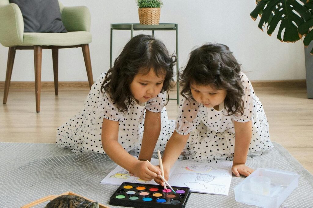 Twin children coloring on floor