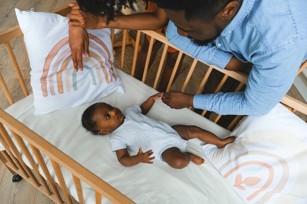 Baby in crib with parent looking over