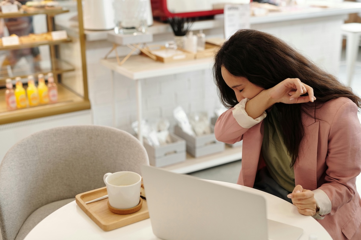 Person sneezing with arm over nose