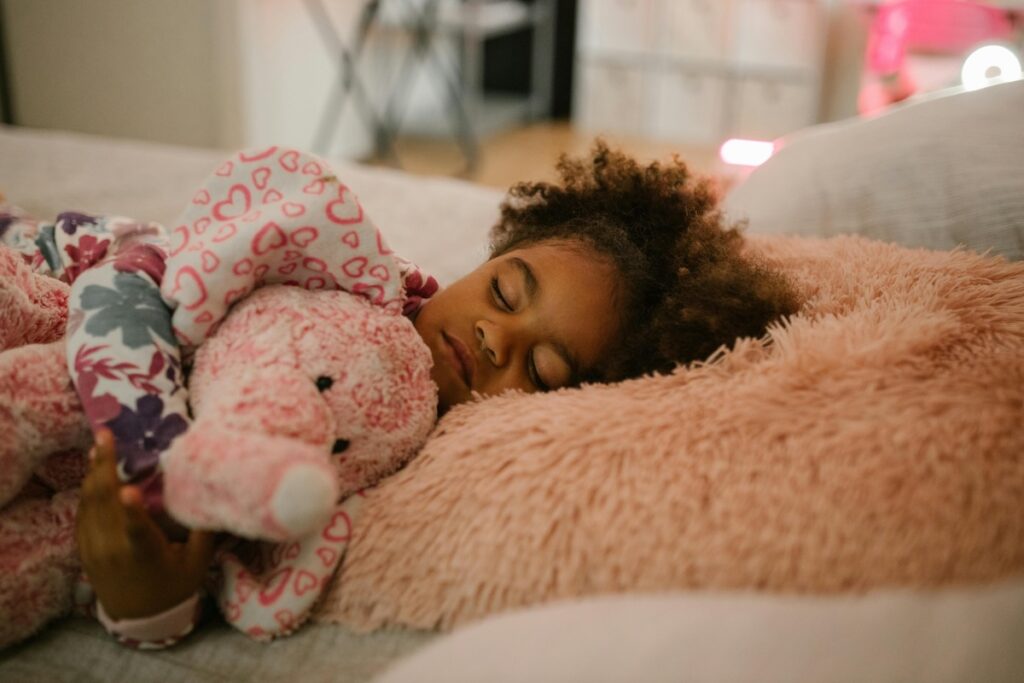 Toddler sleeping in bed with elephant stuffed animal