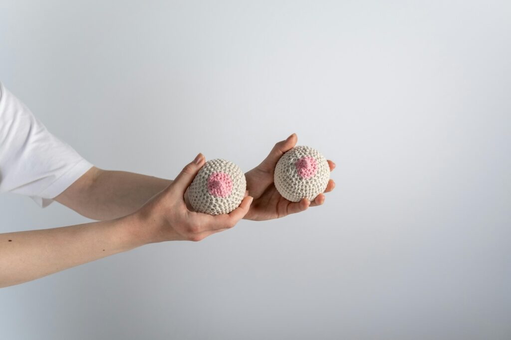 Hands holding hacky sacks styled as breasts