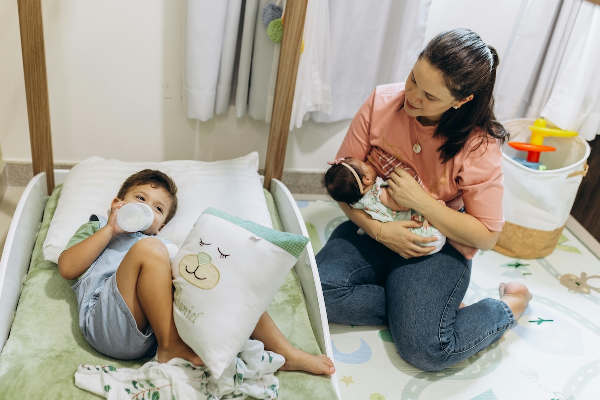 Parent breastfeeding baby with toddler nearby