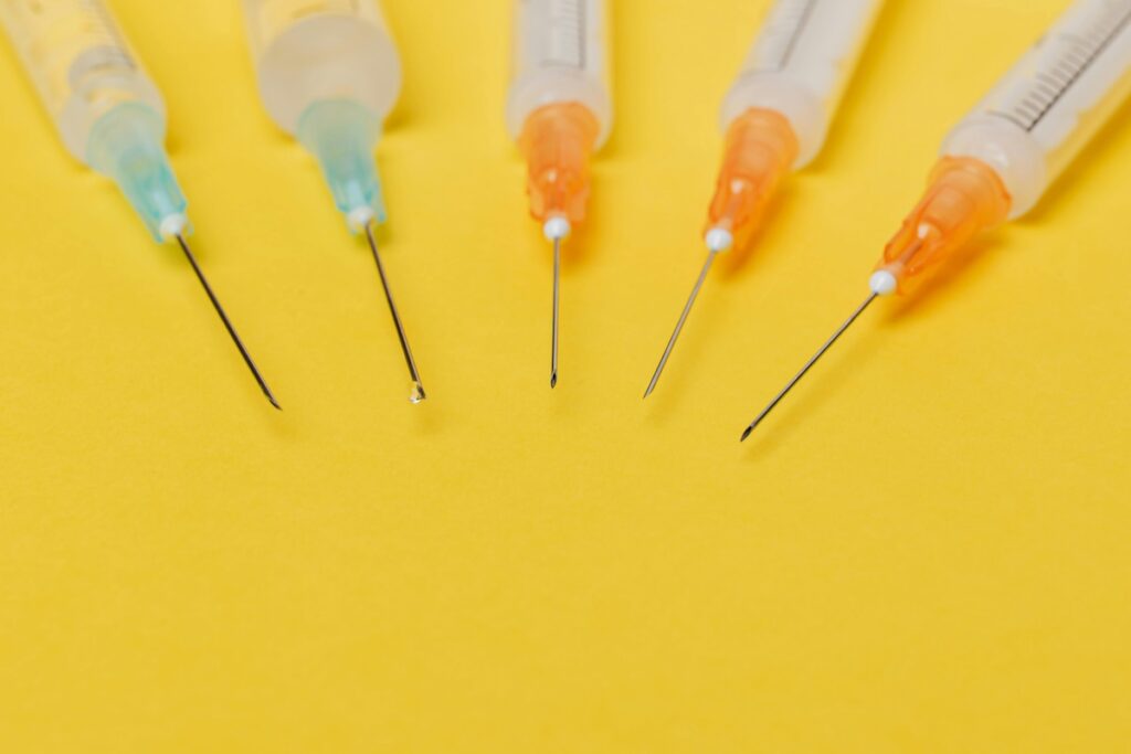Five injectable needles on a yellow background